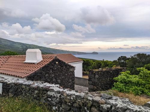 a house with a stone wall and a view of the ocean at Casa das Hortênsias in Horta