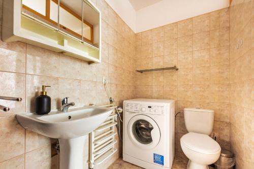 ein Badezimmer mit einer Waschmaschine und einem Waschbecken in der Unterkunft VacationClub – Apartament Waryńskiego 14C in Szklarska Poręba