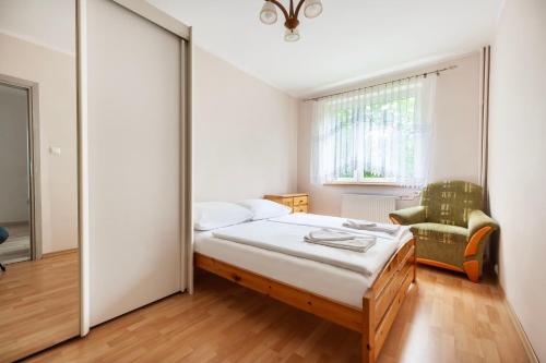ein Schlafzimmer mit einem Bett, einem Stuhl und einem Fenster in der Unterkunft VacationClub – Apartament Waryńskiego 14C in Szklarska Poręba