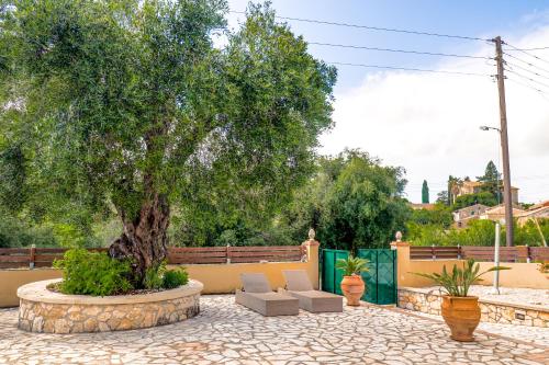 a tree in a patio with two chairs and a tree at Moute House by Corfuescapes in Ágioi Doúloi