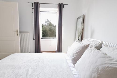 a white bed with white pillows and a window at Moute House by Corfuescapes in Ágioi Doúloi