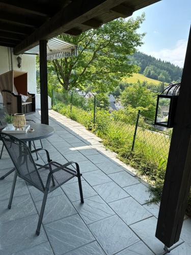 una mesa y una silla en un patio con vistas en Urlaubsschmiede Winterberg, en Winterberg