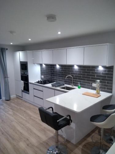 a kitchen with white cabinets and a kitchen island with chairs at luxury in Ballyvoy
