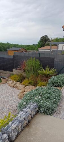 a garden with rocks and plants in front of a fence at chambre d'hôte La Paisible in Treize-Vents