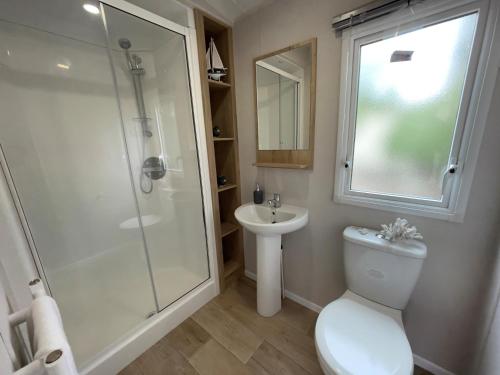 a bathroom with a shower and a toilet and a sink at Mersea Retreat in West Mersea