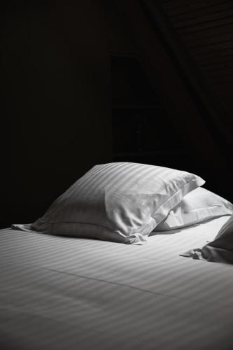 two white pillows sitting on a bed in a dark room at pieuX in Montreuil-sur-Mer
