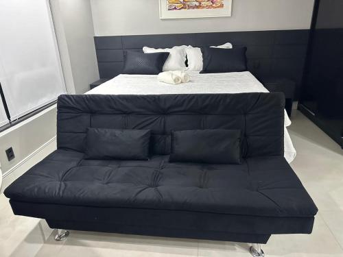 a bed with a black couch in a room at Flat Hotel Tropical Executive Praia Ponta Negra in Manaus