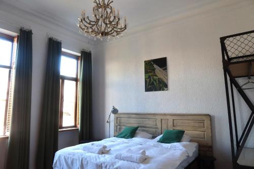 a bedroom with a bed with white sheets and a chandelier at Wonderer House in Batumi's Old City in Batumi