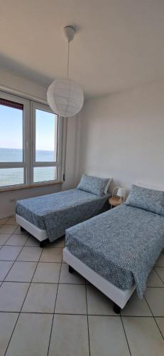 a bedroom with two beds and a large window at LAMAR SUITES Seafront Apartments in Misano Adriatico