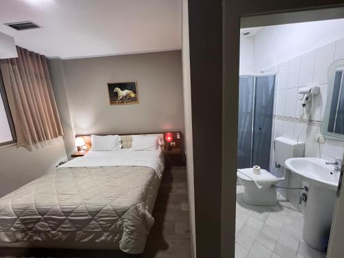 a bedroom with a bed and a bathroom with a sink at Bobi Hotel in Shkodër