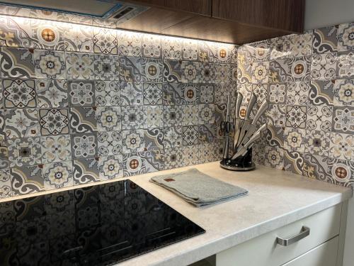 a kitchen with a counter with tiles on the wall at Luxuria Modern Apartments - Self Check-in in Šiauliai