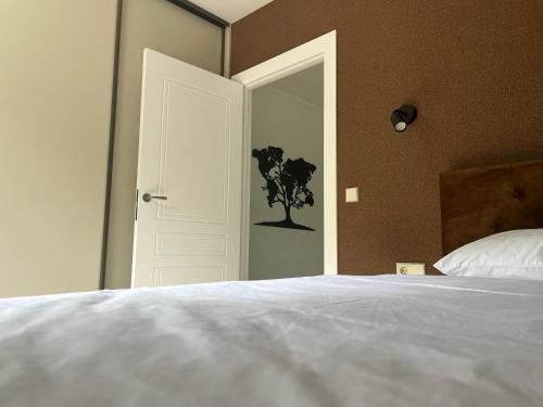 a bedroom with a white bed and a door with a tree on it at Luxuria Modern Apartments - Self Check-in in Šiauliai