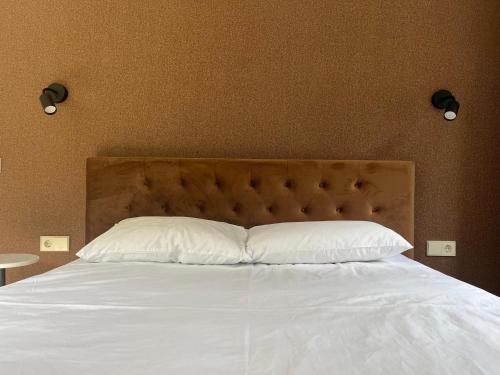 a bed with white sheets and pillows in a bedroom at Luxuria Modern Apartments - Self Check-in in Šiauliai