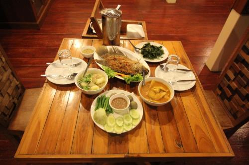 a wooden table with plates of food on it at Panvaree Resort in Ratchaprapha