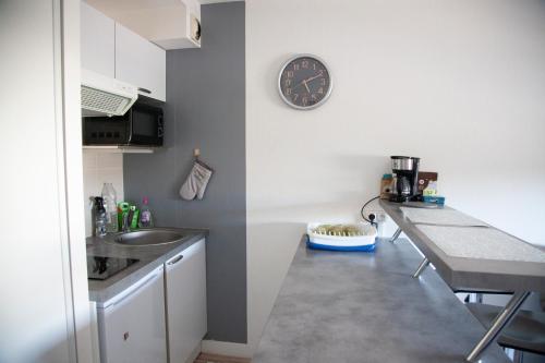 une cuisine avec un évier et une horloge murale dans l'établissement atlantis, à Vannes