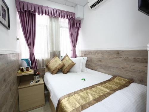 1 dormitorio con 1 cama grande y cortinas moradas en Super Inn, en Hong Kong