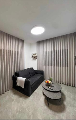 a living room with a black couch and a table at פסגת יובלים 2 in Qiryat Shemona