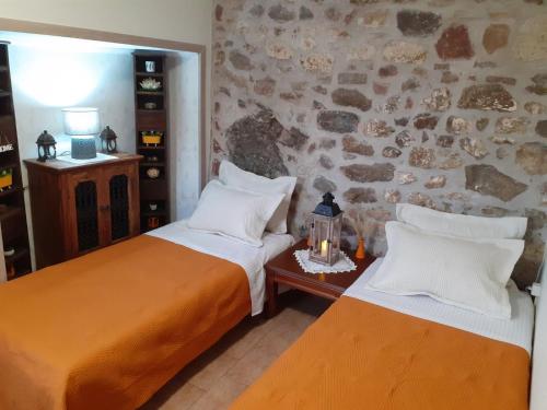 two beds in a room with a stone wall at Stone Clock's House in Nafpaktos