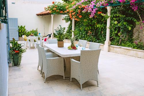 a table and chairs on a patio with flowers at Villa Ardura - island holiday residence **** Bol. Island Brač in Bol