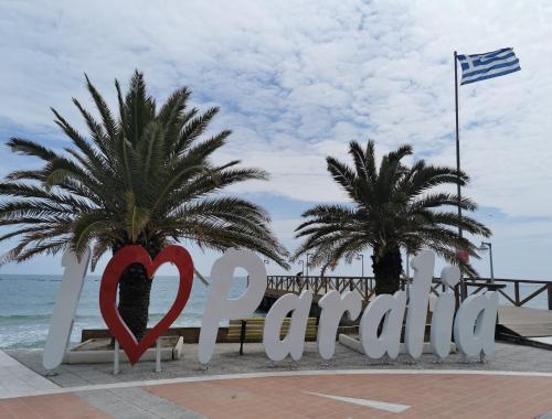 a sign for the beach with two palm trees at Villa Olympia in Paralia Katerinis