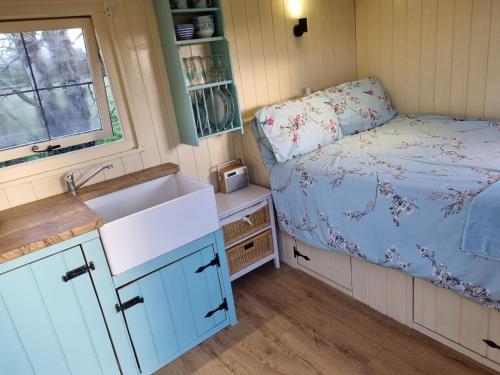 eine Küche mit einem Waschbecken und ein Bett in einem Zimmer in der Unterkunft Delilah the shepherd's hut in Sidlesham