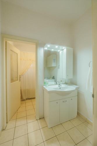 a white bathroom with a sink and a mirror at AKANTHOS Rental House in Korinthos