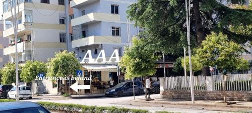un hombre está parado frente a un edificio en AAA Apartment, en Berat