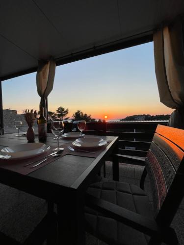 uma mesa com copos de vinho e vista para o pôr-do-sol em Mobile Home L&L em Drage