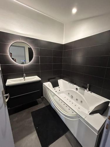 y baño con bañera, lavabo y espejo. en Maison à chateaugay balneo en Châteaugay