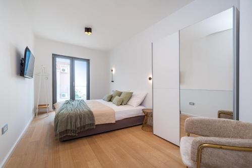 a white bedroom with a bed and a chair at Villa Cvita east in Primošten