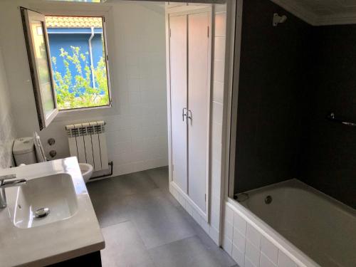 uma casa de banho com um lavatório, uma banheira e uma janela em Villa La Palmera y El Mar em Naveces