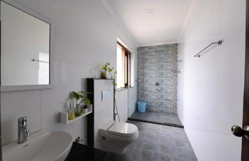 a bathroom with a white toilet and a sink at Farm Stay in Neemrana I 3 BHK with Pool & Chef I Close to Nature - Poshpad in Behror