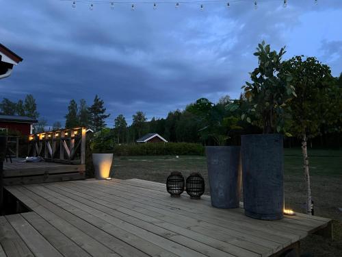 a wooden deck with two large vases on it at Villa Granhede -sjöläge med badtunna, eldstad med mera in Torsby