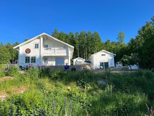 uma casa branca numa colina com flores roxas em Stunning Tiny House Tree of Life at lake Skagern em Finnerödja