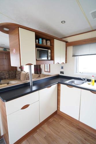 a kitchen with white cabinets and a sink at Manor Park Hunstanton pets go free Linen Included in Hunstanton