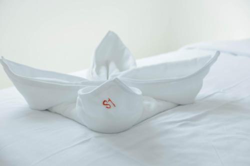 a white origami boat sitting on a bed at S1 Trang Hotel in Trang