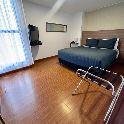 1 dormitorio con 1 cama, TV y silla en Súper Apartasuite en muy buena ubicación, en Bogotá