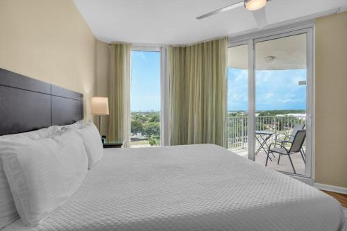 a bedroom with a large white bed and a balcony at Palms of Destin 2710 in Destin