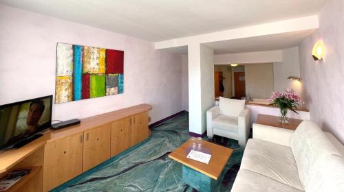 a living room with a couch and a television at Hotel Am Hirschhorn - Wellness - Spa - and more in Wilgartswiesen