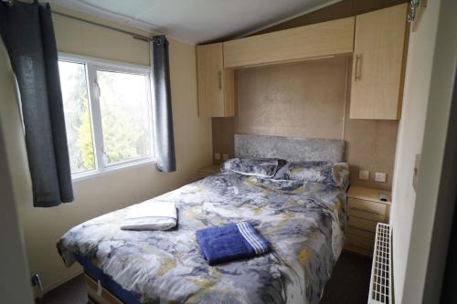 Schlafzimmer mit einem Bett mit blauer Bettwäsche und einem Fenster in der Unterkunft Manor at Manor Park Hunstanton WiFi pets go free in Hunstanton