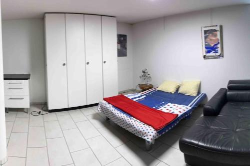 a bedroom with a bed and a cabinet and a couch at Basel - 5 mins away - Modern Basement Studio with Kitchen 35m2 in Muttenz in Muttenz