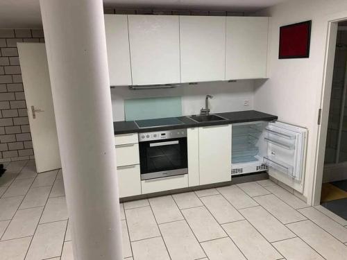 a kitchen with white cabinets and a stove top oven at Basel - 5 mins away - Modern Basement Studio with Kitchen 35m2 in Muttenz in Muttenz