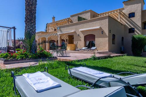 a backyard with a house with a table in the grass at Palais les sources de l'atlas & spa in Marrakesh