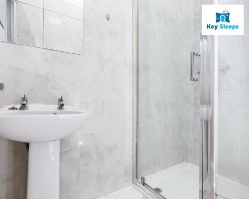 a white bathroom with a sink and a shower at Stunning Three Bedroom House At Keysleeps Short Lets Cleethorpes With Free Parking & Beach Location in Cleethorpes