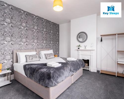 a bedroom with a large bed and a wall with floral wallpaper at Stunning Three Bedroom House At Keysleeps Short Lets Cleethorpes With Free Parking & Beach Location in Cleethorpes