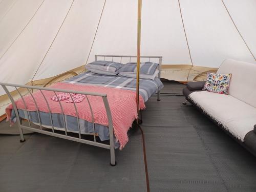 a bed and a couch in a tent at Tryfan Pen Cefn Farm Bell Tent in Abergele