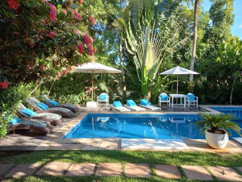 a swimming pool with lounge chairs and umbrellas next to it at Pousada Jardim Das Margaridas in Trancoso