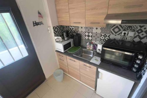 a small kitchen with a sink and a microwave at Summer House with Garden and Fruit Trees in Nea Makri