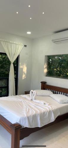 um quarto com 2 camas com lençóis brancos e uma janela em La Morenita em Puerto Triunfo