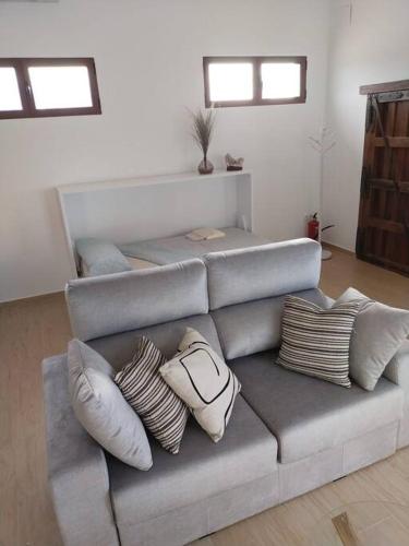 a living room with a gray couch with pillows at Finca Santa Lucía Alojamientos in Mazarambroz
